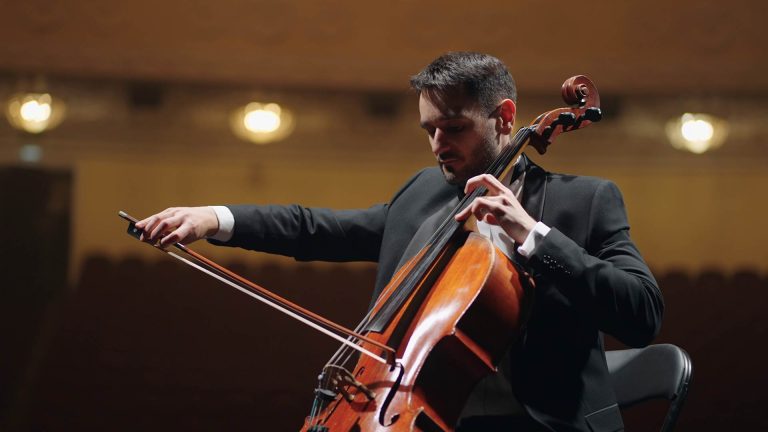 A cellist is playing his acoustic cello