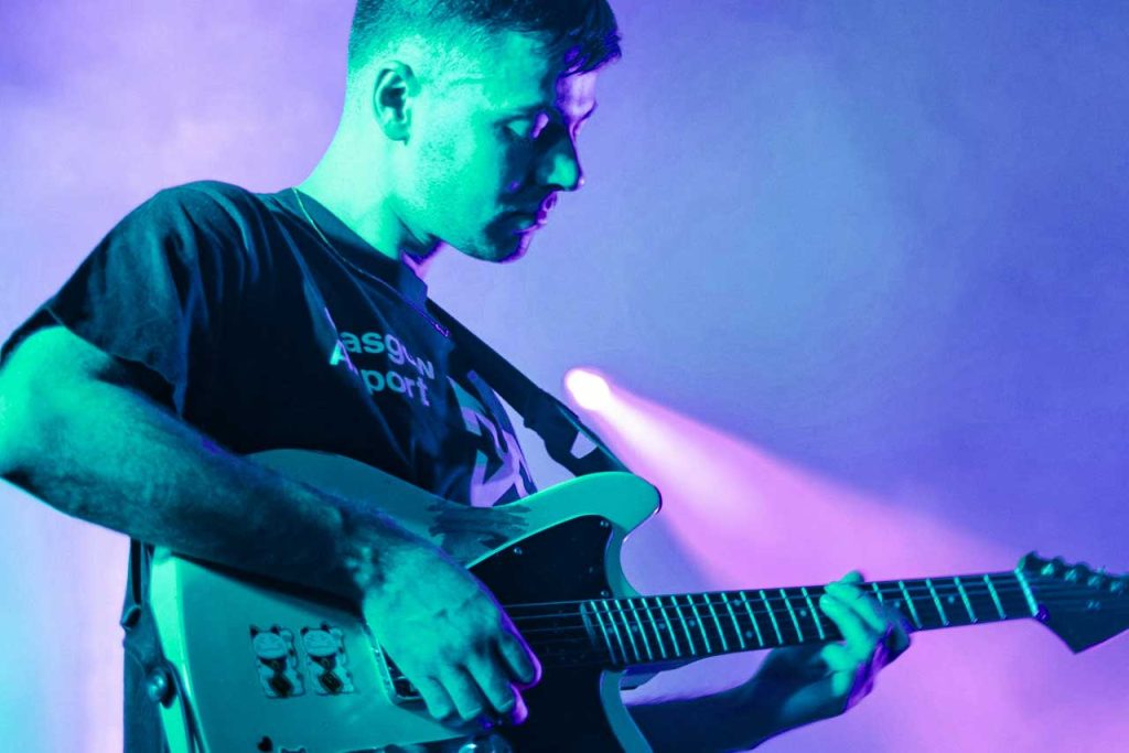 A guitarist playing electric guitar on stage with lighting