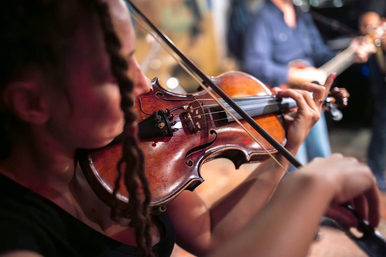 a female violinist is playing her acoustic violin amplified with a pickup